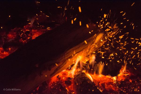 Close-up shot of sparks and hot embers in a campfire.